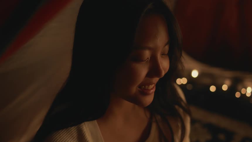 A close up of a womans face as she looks down and up and then smiles
