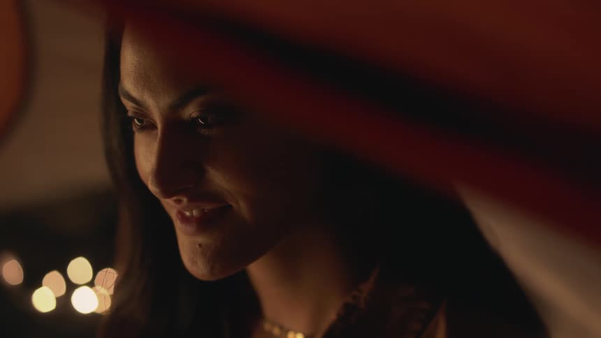 A woman is smiling and sitting inside of a tent