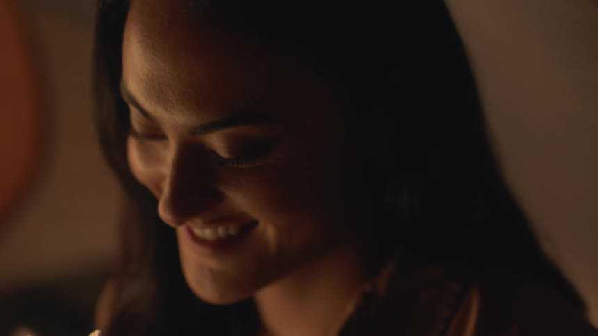 A woman is smiling while sitting inside of a tent