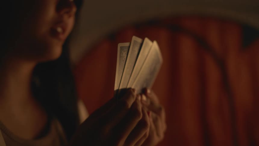 A close up of a woman holding playing cards in her hands and smiling