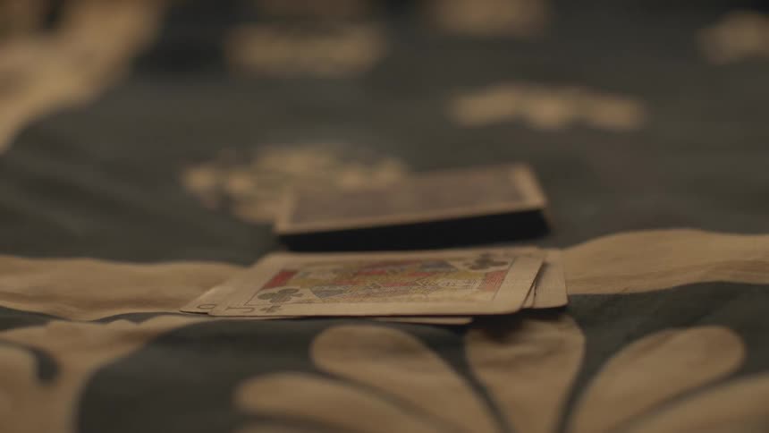 A person is dealing poker cards on top of a stack while there is another deck of cards next to it faced down