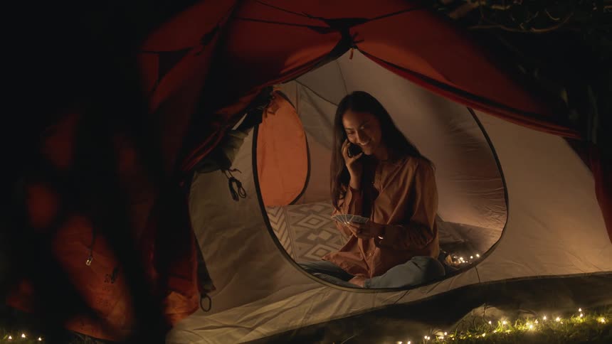 A woman is talking on her phone while camping outdoors