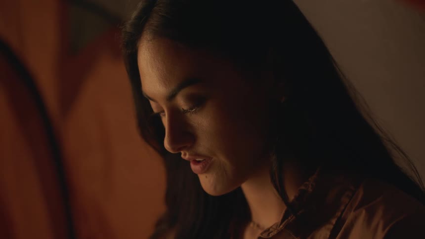 A young woman is inside of a tent around the night time