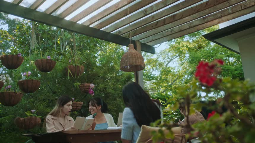 A group of friends sitting on a table in the garden talk to each other at daytime