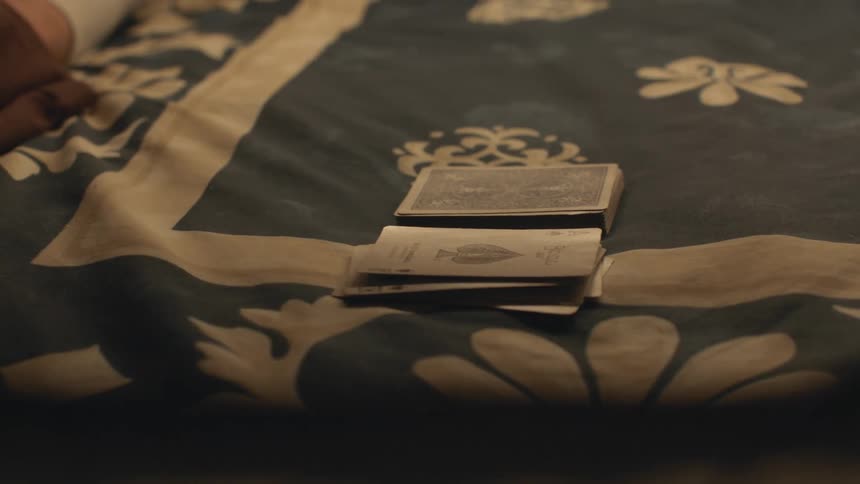 Close up of the hands of a couple of friends playing a simple game of cards over the bed