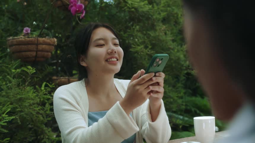 A young asian woman is on her phone and is smiling