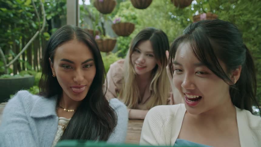 Three friends are sitting outdoors and taking a selfie