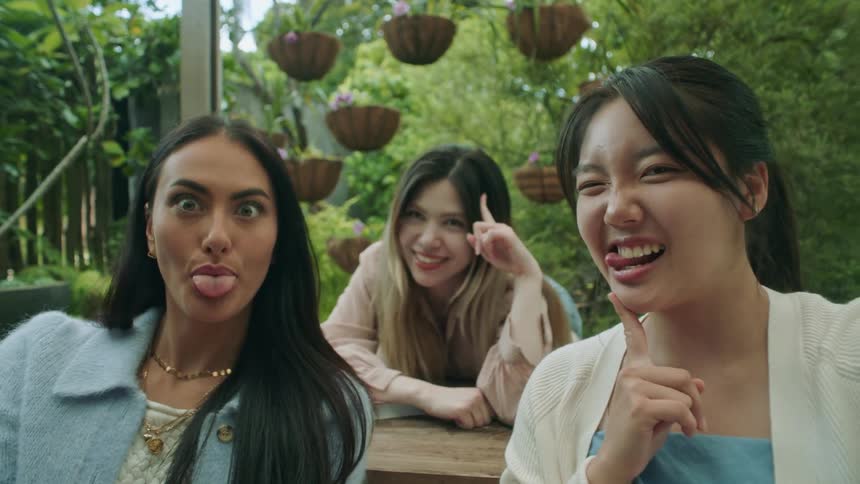 Three friends are sitting outdoors together in summer
