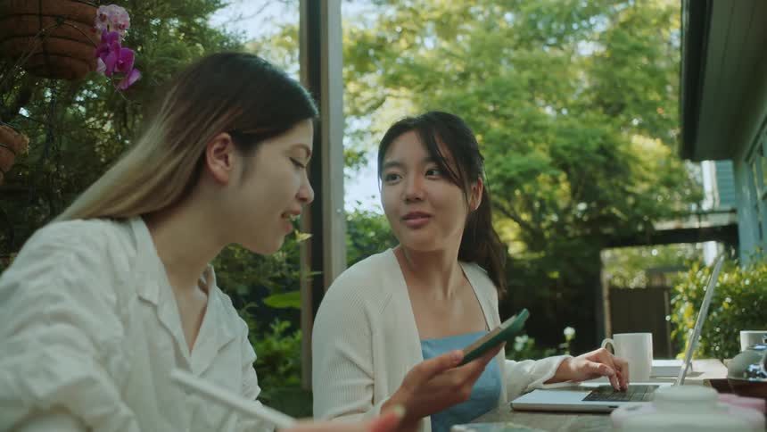 Two women talk and look at a cell phone