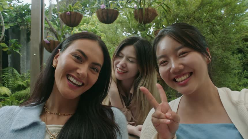 Three women sitting outside smiling and posing for a picture