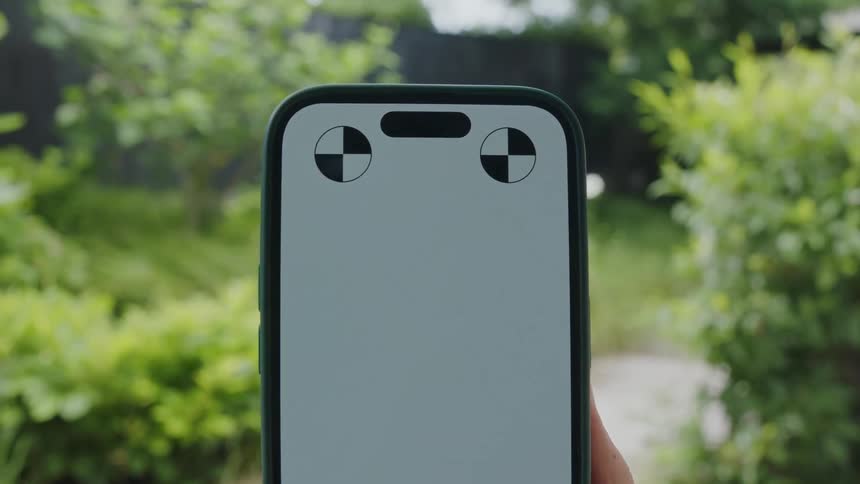 Hand holds up smartphone against the green field