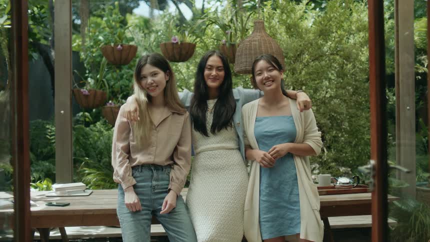 Three friends are standing outdoors and smiling in the portrait