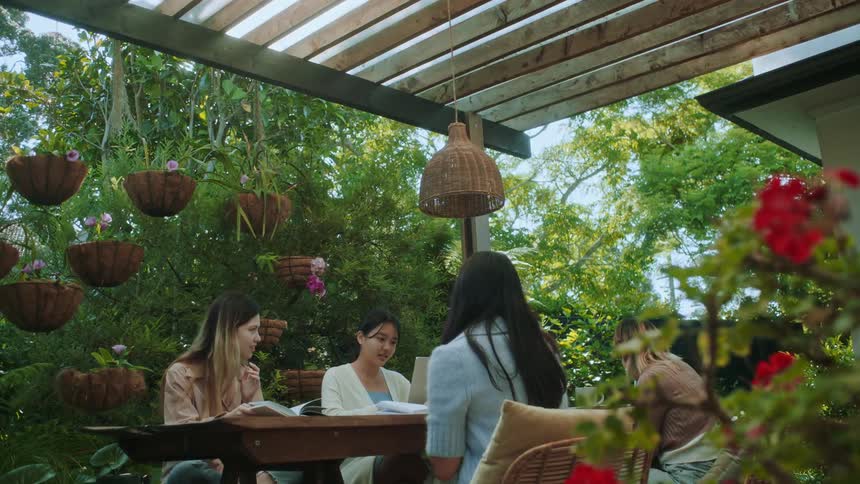 A group of friends sitting on a table in the garden talk to each other at daytime