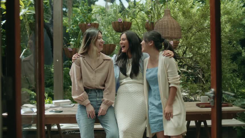 Three friends reclined on a table in the garden talk and laugh together