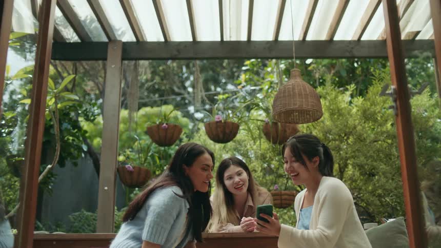 A group of friends sitting on a table in the garden talk to each other at daytime