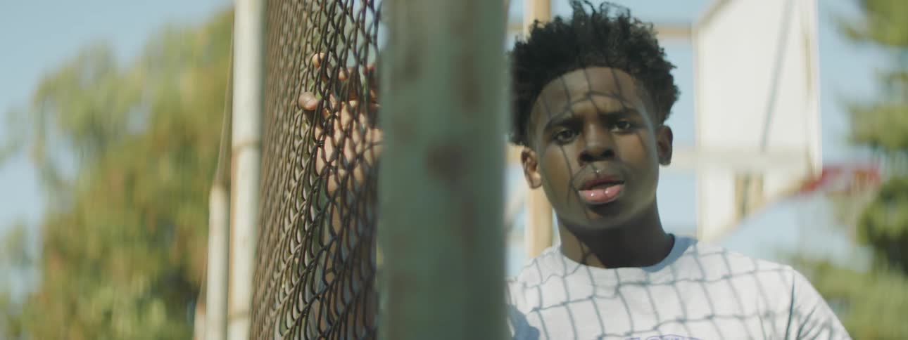 A man in a white shirt puts his hand on a fence