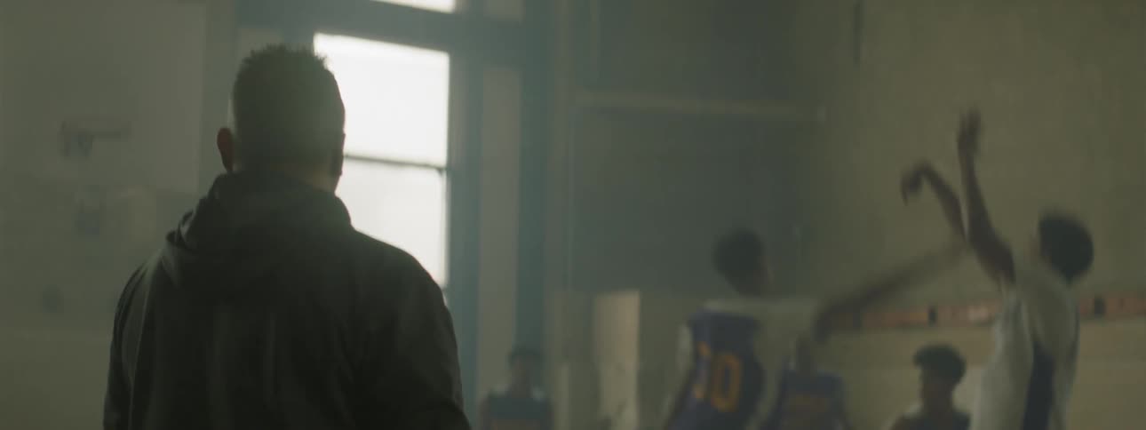 A coach watches on as players have a game of basketball