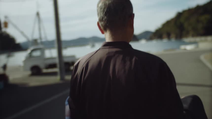 A man carrying a jacket through a parking lot