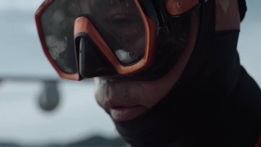 An older man with a mustache is wearing a diving mask as he looks at the water