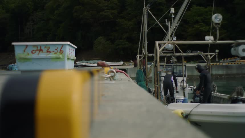 Men wearing wet suits move about boat at dock