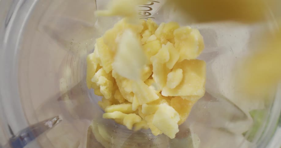 Fruit is being put inside of a blender