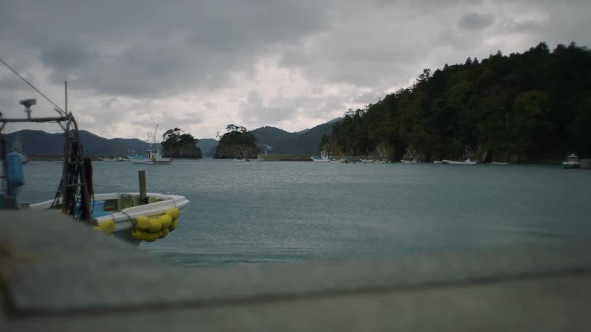A fishing boat slowly departs from the dock on a lake in the mountains at morning