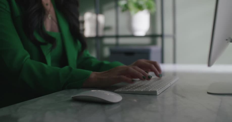 A woman is typing on her computer while sitting indoors