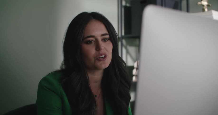 A woman is smiling and talking to someone via computer