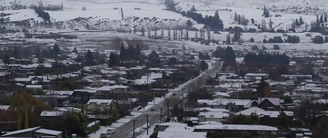 An aerial view of a snow covered village with a street down the middle and houses on either side