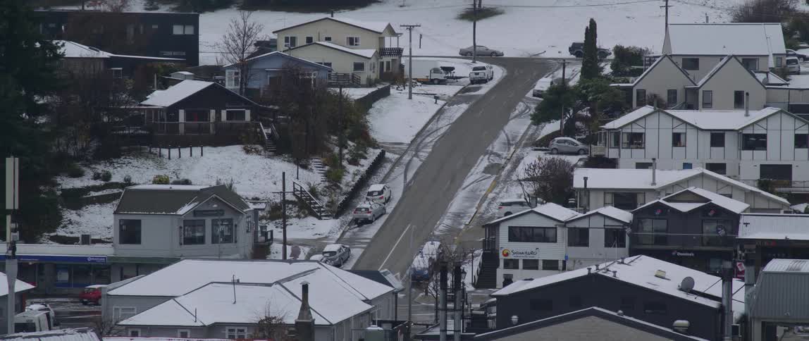 Cars are driving through a suburban neighborhood in winter
