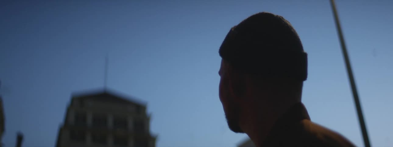 A silhouette of a mans head looking up at the sky and buildings