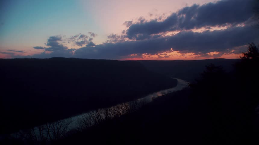 Landscape of river and field being silhouetted against the sky at sunset