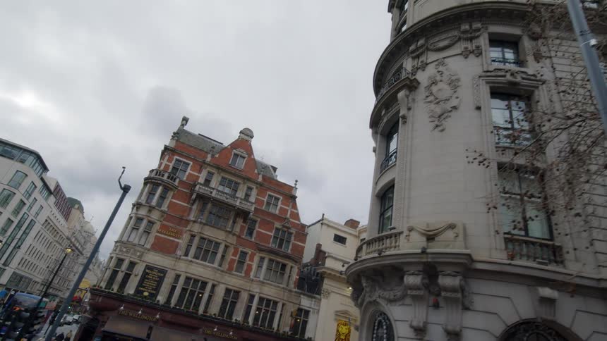 A drone view of a city street where people are walking and tall buildings