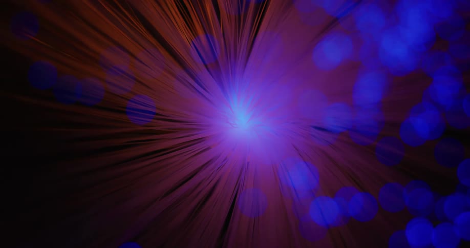 Red and yellow rays of light rotate as a glowing green and blue orbs move and change colors