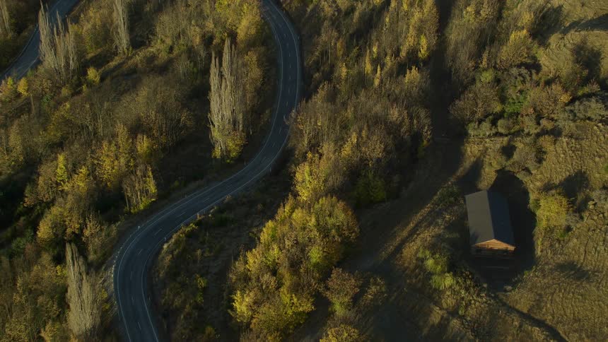 Highway winds through woods near farmhouse