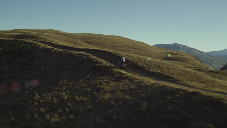 A person riding a dirt bike on a trail up a large hill