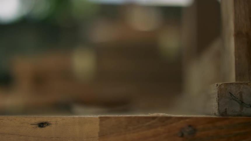 A hammer hits a board hard and dust flies into the air