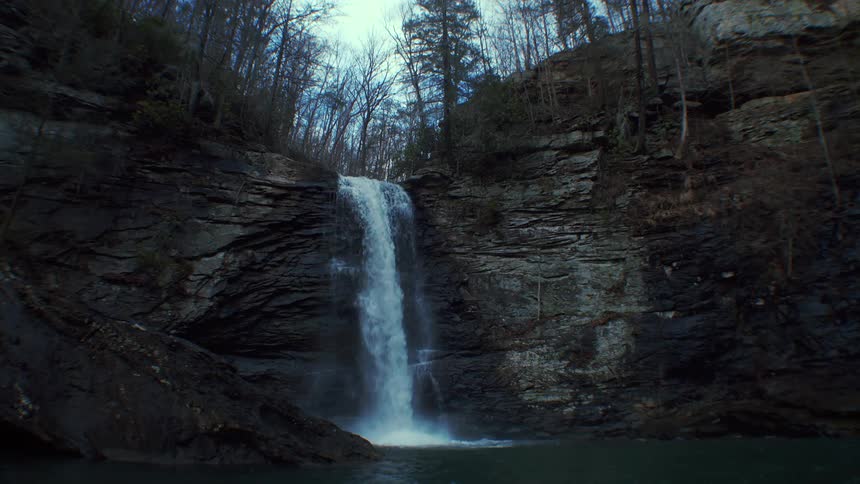 A waterfall rushes over a cliff in a canyon