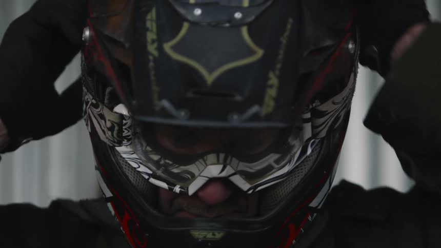 Male biker with helmet and jacket wears goggles
