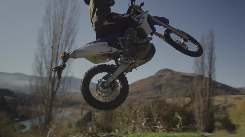 A man is doing tricks on his motorcycle in the wilderness