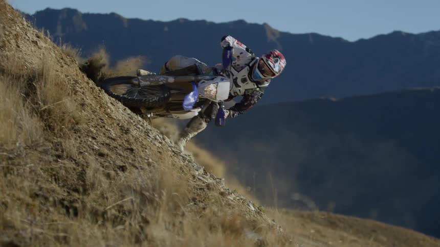 Biker rides dirt bike uphill in the hills