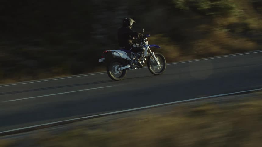 A person riding a motorcycle on a paved road in the daytime