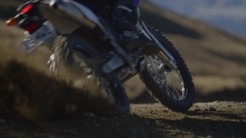 A person is riding a dirt bike on a trail in the middle of the day time