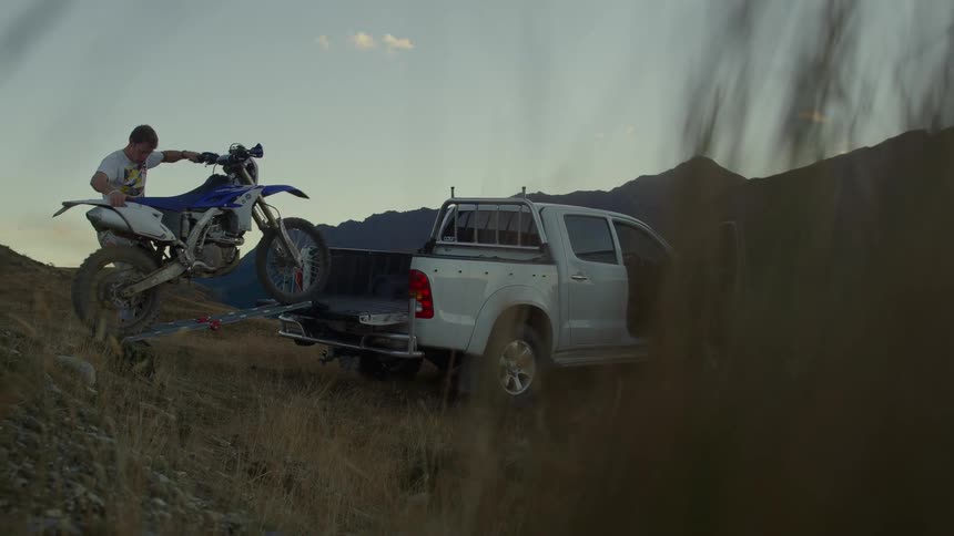A man is unloading a motorcycle from his truck