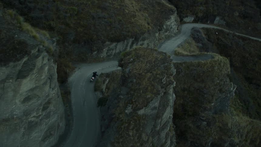 Aerial view of biker riding motorcycle on winding mountain road