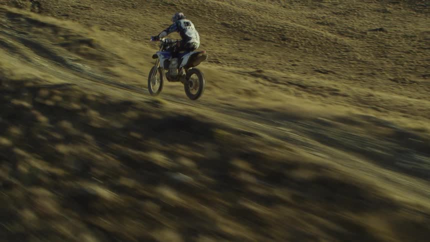 Biker rides dirt bike in the hills