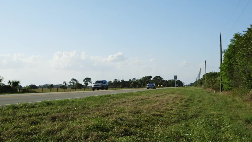 Vehicles travel along a rural road during the day