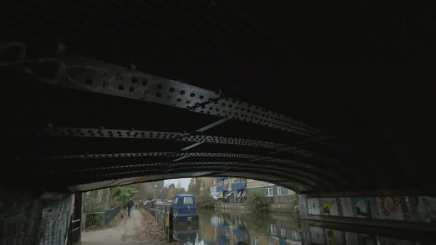 The roof of an arched bridge under a canal way with a boat docked