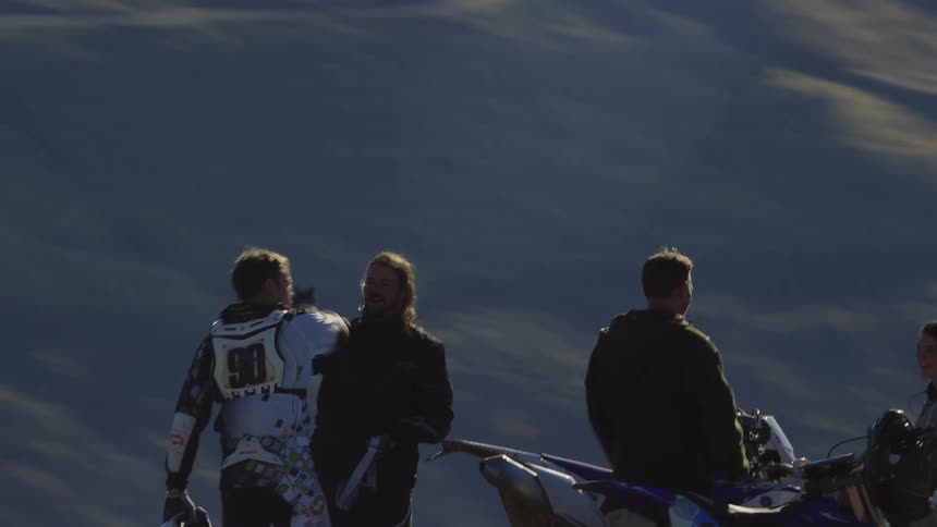 Aerial orbiting view of a group of motorcycle riders celebrating atop a mountain