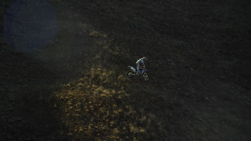 A young man is riding his motor bike around the nature area